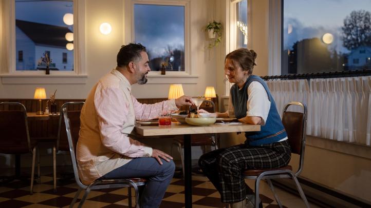 Two diners sit together at a table in Longfellow Restaurant in the Evangeline Hotel waiting for their meals.